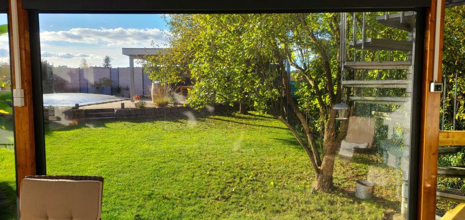 Blick durch das Wetterrollo auf den Garten
